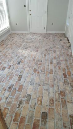 an empty room with brick flooring and white doors