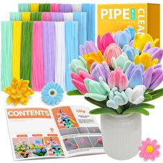 a vase filled with lots of colorful flowers next to an open magazine and paper clips