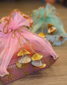 a pink bag sitting on top of a wooden table next to other bags with gold decorations