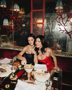 two women sitting at a table with food