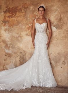 a woman in a wedding dress standing against a wall