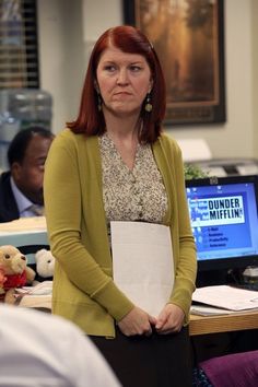 a woman standing in an office holding a piece of paper