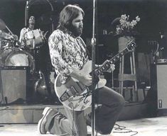 a black and white photo of a man playing an electric guitar in front of a microphone