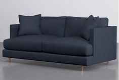 a blue couch sitting on top of a hard wood floor next to a white wall