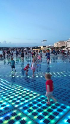 many children are playing in the water at an outdoor pool with blue tiles on it