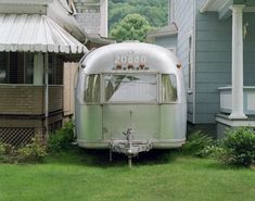 an old airstream parked in front of a house on the side of a road