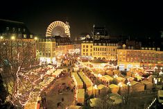 an aerial view of a christmas market in the city at night with ferris wheel in background