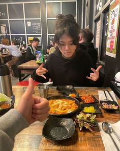 a woman sitting at a table with food in front of her and pointing to the side