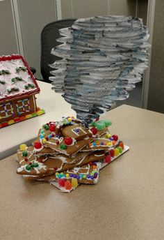 two gingerbread houses are on the table and one is made out of construction paper