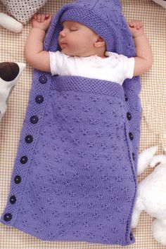 a baby sleeping in a blue blanket next to stuffed animals