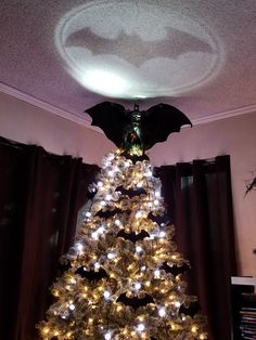 a decorated christmas tree with lights in the shape of batman's wings and bats