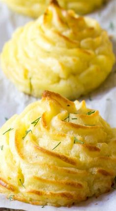 three baked potatoes on wax paper with some green sprigs in the middle and one is yellow