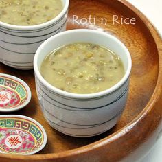 three bowls filled with soup on top of a wooden tray next to two small plates