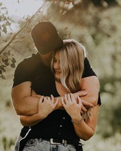 a man and woman embracing each other under a tree