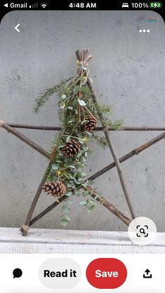 a star made out of sticks with pine cones and greenery hanging from it's sides