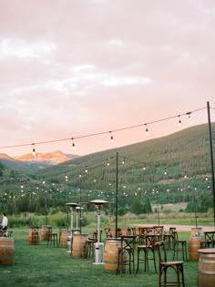 an outdoor setting with tables, chairs and string lights in the mountainside area at dusk