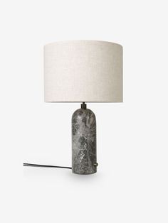 a table lamp with a white shade on it and a black marbled object next to it