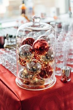 a clochet filled with christmas ornaments on top of a red tablecloth covered table