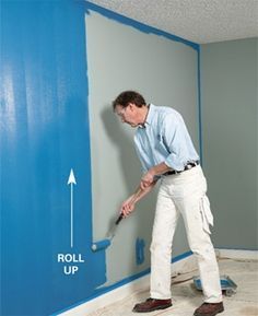 a man is painting the wall with blue paint