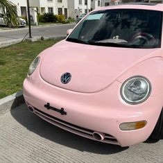 a pink volkswagen beetle parked on the side of the road