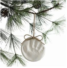 a white ceramic ornament hanging from a pine tree