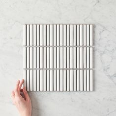 a white marble tile with vertical lines on the bottom, and horizontal bars in the middle