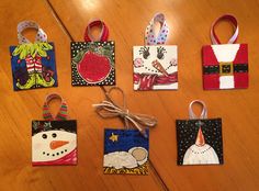 small christmas gift bags with designs on them sitting on a wooden table next to a string