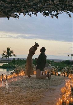 a man and woman standing next to each other in front of candles on the ground