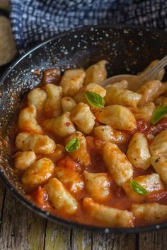 a pan filled with pasta and sauce on top of a wooden table