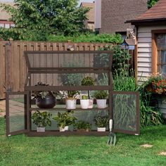 an outdoor garden area with potted plants and gardening tools on the grass in front of a house