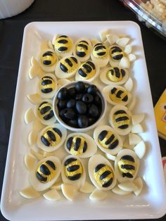 a white plate topped with deviled eggs covered in black olives and bee decorations