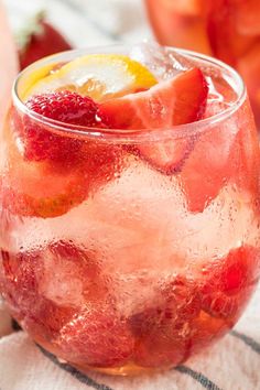 two glasses filled with ice and strawberries on top of a table next to each other