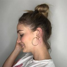 a woman with ear piercings on her left side of her head, wearing a white t - shirt