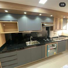 an empty kitchen with black counter tops and wooden cupboards on the wall above it