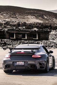 a grey sports car parked in front of a mountain