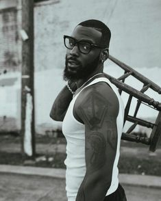 a black and white photo of a man with glasses holding a baseball bat in his hand