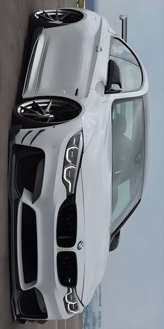 the front end of a white car hanging on a wall with city buildings in the background