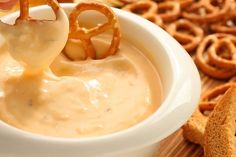 a bowl of dip with pretzels being dipped into the dip and dipping sauce