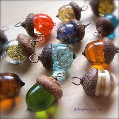 there are many different colored glass beads on the table with acorns in them