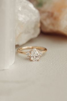 a diamond ring sitting on top of a table next to a white vase and rock