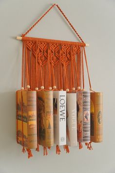 an orange macrament hanging on the wall with some books in front of it