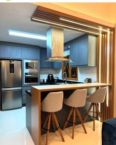 a modern kitchen with stainless steel appliances and bar stools in front of the counter