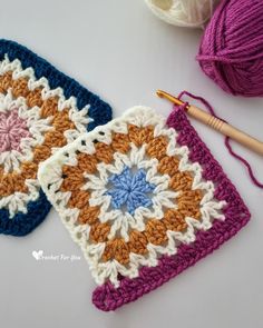 two crocheted grannys with yarn next to them