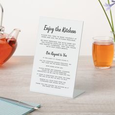 a tea pot and cup on a table next to a sign that says enjoy the kitchen