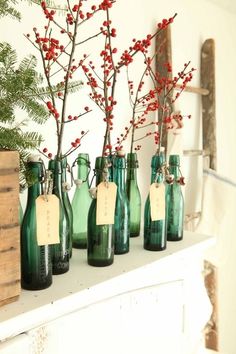 several green glass bottles with red berries in them