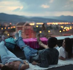 three people laying on the roof of a building with their feet up in the air