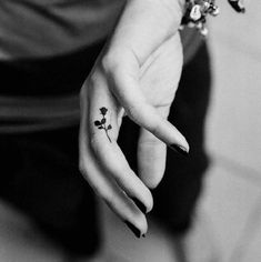 black and white photo of woman's hand with small flower tattoo on the middle finger