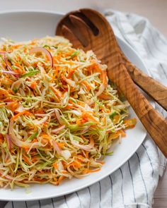 a white plate topped with coleslaw and carrots next to a wooden spoon