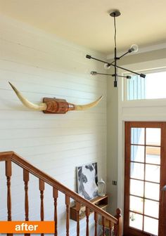 a wooden banister with two horns mounted on the wall above it and another light fixture