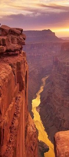 the sun is setting at the edge of a canyon with a river running through it